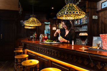 Bartender preparing cocktail in traditional pub with stained glass lamps