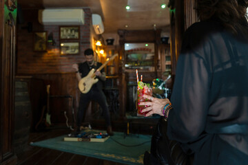 Woman holding cocktail enjoying live music at pub