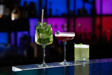 row of various colourfull alcoholic cocktails on a bar desk. Glasses of differen shapes. selective focus