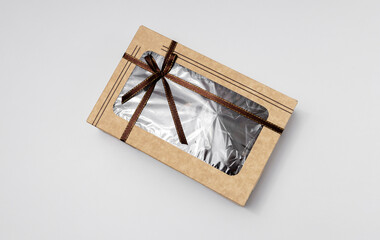 Top view of paper box with brown ribbon and bow on white background. Box for presents wrapping or product sale