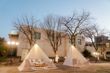 Outdoor lounge areas with draped tents and seating, providing a stylish and comfortable setting....