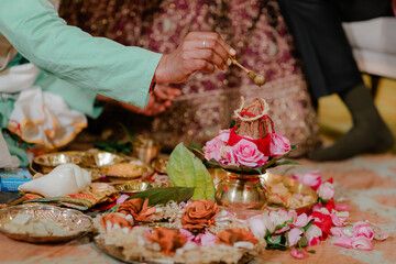 Hindu Wedding Ritual: Hand pouring water over coconut atop floral arrangement, symbolizing tradition, spirituality, and new beginnings in marriage.