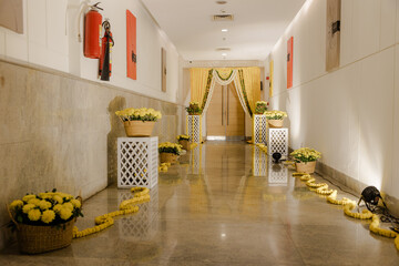 Hallway decorated with yellow flowers and garlands, leading to draped entrance, creating a festive...