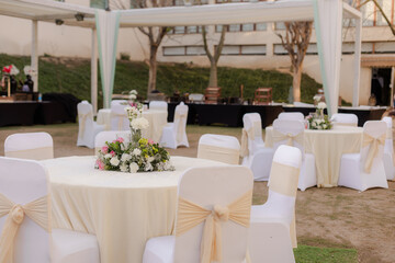 Elegant event space: decorated round tables, white chairs, and floral centerpieces create a charming atmosphere for celebrations and gatherings.