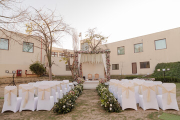 Outdoor wedding setup with floral arch, white chairs, and aisle flowers. A beautiful and intimate ceremony. Love is in the air!