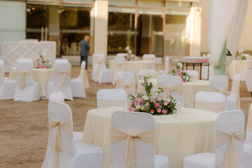 Elegant outdoor event setup with floral centerpieces and white chair covers, creating a festive atmosphere. Perfect for celebrations!