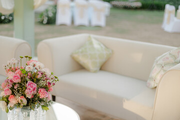 Elegant outdoor seating area with fresh floral arrangement on glass table in soft focus background. Serene and sophisticated decor.