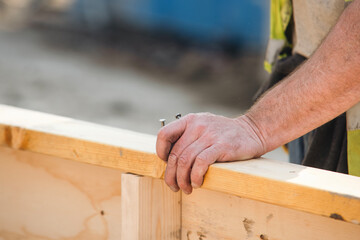 Close-up of hands of builder joiner using plywood and timber to asseble shutter panel for concrete...
