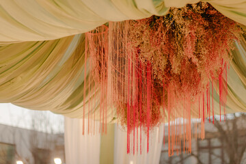 Elegant ceiling decor featuring flowing floral arrangements with hanging strands of soft, pastel...