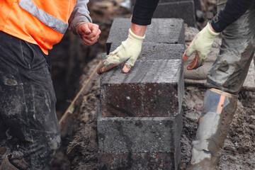 Hard-working bricklayer laying concrete blocks on housing site helping eliminate housing crisis by building more affordable houses concept