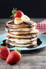 Pancakes with chocolate and fruit on wooden table