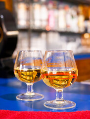 Close-Up of Two Whisky Glasses on Blue Bar Counter – Golden Scotch Liquor in Snifters with Reflections, Cozy Nightlife Atmosphere, Elegant Drink Presentation