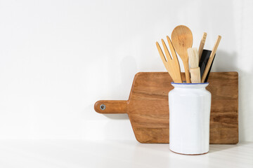 Kitchenware in a ceramic vase and cutting board on white cooking background with copy space for recipes and menus