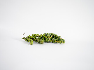 A horizontal green peppercorn sprig with dense clustered berries, featured on white background to...