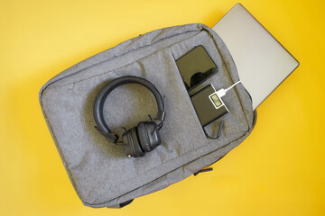 A gray urban backpack with headphones, laptop, smartphone and power bank, ideal for daily commutes and organizing tech gear. Photo