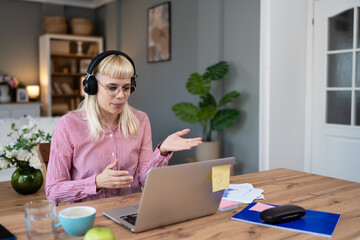 Young freelance business woman having video call conference on laptop computer while sitting and...
