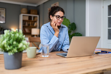Young freelance business woman having video call conference on laptop computer while sitting and...