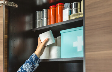 Woman hand organizing emergency food pantry in kitchen. 72 hours survival kit concept.