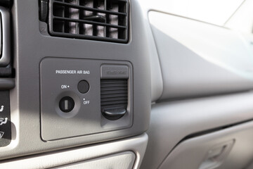 Obraz premium Close up of passenger airbag control switch and power outlet port on the dashboard of an early 2000s American pickup truck.