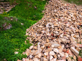 Pile of construction stones and rubble on green grass, used for the restoration of Zborov Castle in...