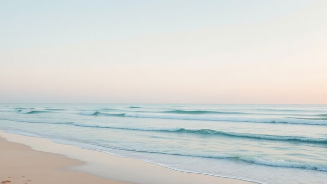 Gentle waves rolling onto a sandy beach at sunrise.