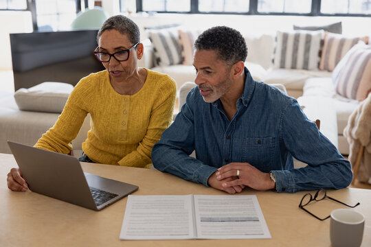 Senior couple looking at paperwork and using a laptop computer for financial investment