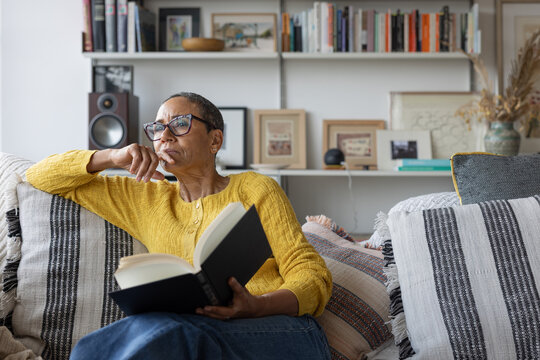 Pensive mature woman reflecting while reading a book.
