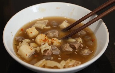 Savory soup with various ingredients served in a clean bowl using chopsticks during mealtime