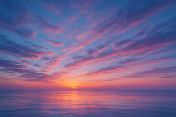 Obraz premium Peaceful ocean view at sunset with vibrant pink, orange, and purple clouds spreading across a clear evening sky..