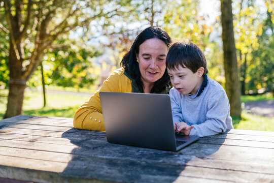 Mother and Son Enjoy Learning on a Laptop Outdoors