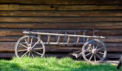old wooden cart with large wheels standing near a wooden Ukrainian house in the yard