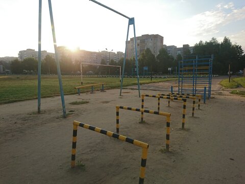 Sunrise over a children's playground with exercise equipment, including monkey bars and climbing frames, creates a nostalgic and active scene