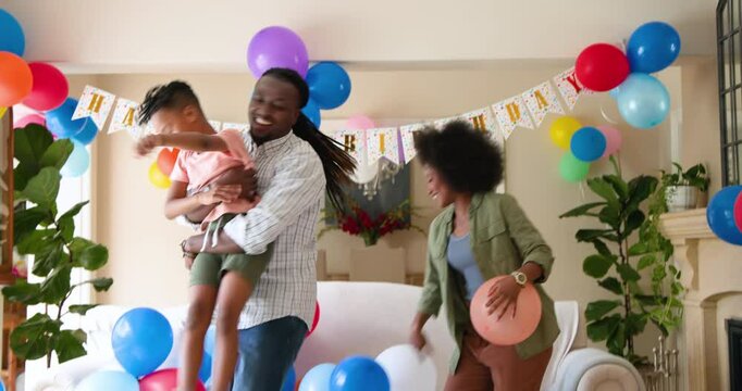 Happy black couple and their multiracial son cuddling and smiling, celebrating boy's birthday at hom