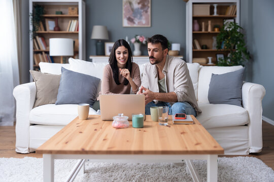 Young intelligent innovative hipster couple presenting their startup new business idea via video call on laptop computer, working at home, talking to potential investor. Modern technology innovation.