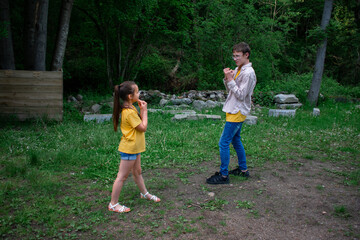Fototapeta premium Capture a moment of playful interaction in nature! This image shows two young people facing each other in a lush, green setting. Ideal for themes of childhood, friendship, and outdoor activities
