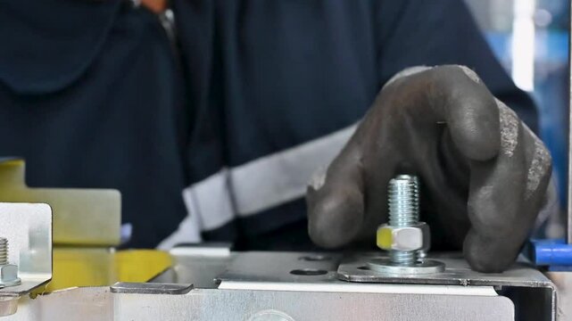 Factory worker tightening nuts and bolts that hold machine parts together