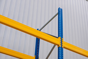 Industrial warehouse racking system with yellow beams and blue uprights. Close-up view of...