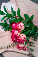 A bouquet of roses is wrapped in a coarse knit woolen sweater.