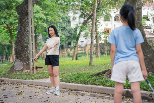 Two friends enjoying badminton in a park during a sunny afternoon in East Asia