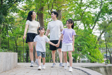 Family stroll in a peaceful park during a sunny day, enjoying quality time together in a scenic green environment
