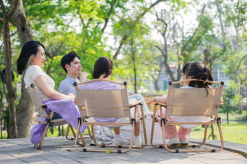Family enjoying a sunny afternoon in the park with laughter and relaxation among friends and children