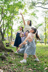 Fototapeta premium Family enjoys a sunny day outdoors, watching something exciting in the sky near a park surrounded by green trees