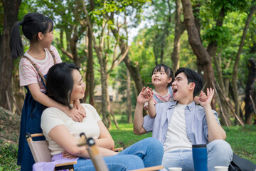 Family enjoying a sunny day in a park with laughter and playfulness around them