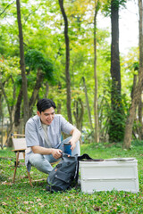 Obraz premium Young man enjoying a calm day in the park while preparing his art supplies amidst nature's beauty and greenery