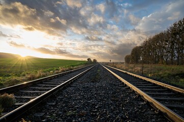 Obraz premium The sun is setting over a train track in the country