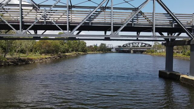 Aerial drone flies under bridge over Maribyrnong River in Melbourne