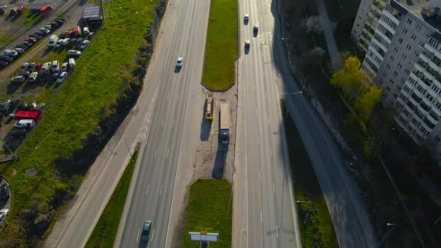 High view over multi lane highway traffic on Laagna tee, Lasnamae. Aerial moving backward above wide main road. Vibrant city district life and long road stretching into the golden hour cityscape