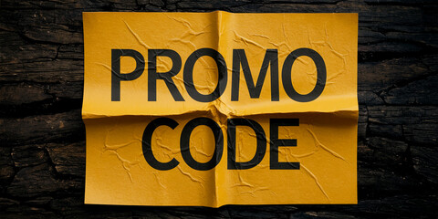 Folded yellow paper with black text "Promo Code" on dark wood background, showcasing a simple, effective promotional concept for discounts or offers