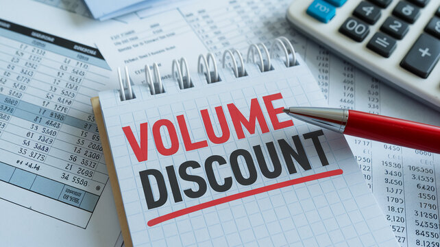 Close-up of notepad showing "Volume Discount" in red and black ink, alongside financial documents and calculator, symbolizing business savings and bulk purchasing