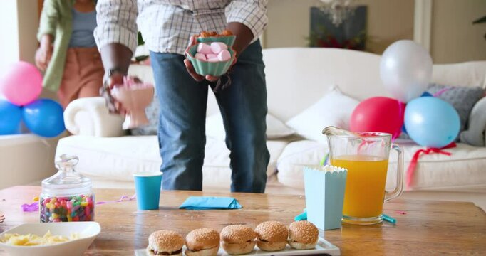 Happy black couple and multiracial son tidying and cleaning living room after celebrating boy's birt